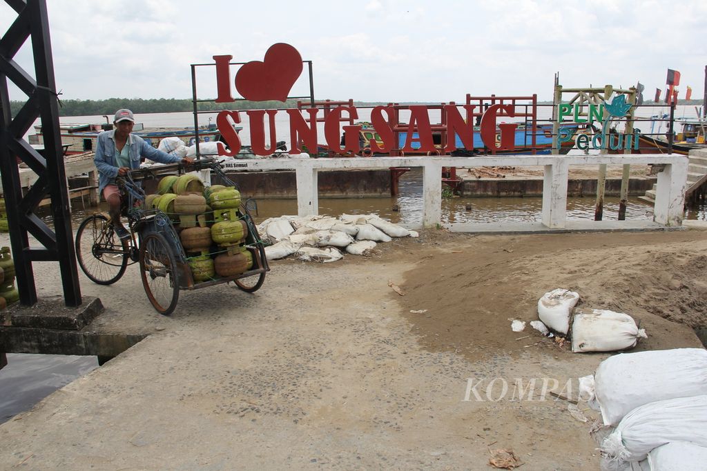 Warga mengendarai becak berisi tabung elpiji yang baru diturunkan dari kapal di Dermaga Sungai Sungsang, kawasan Sungsang, Kecamatan Banyuasin II, Kabupaten Banyuasin, Sumatera Selatan, Minggu (23/1/2022).