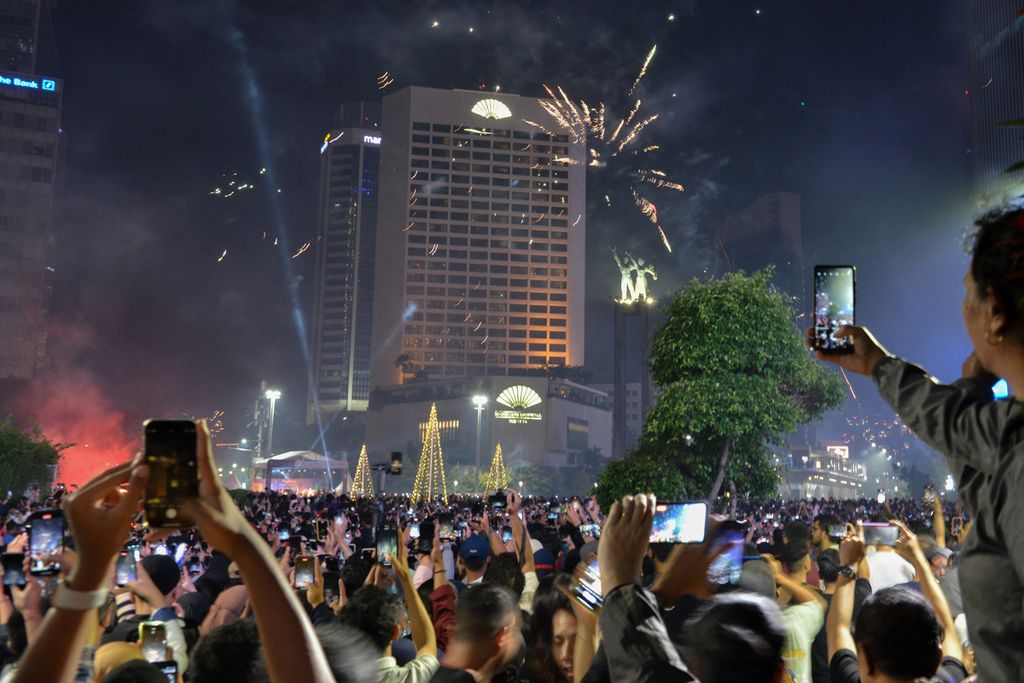 Warga menyaksikan pertunjukan kembang api di sekitaran Bundaran Hotel Indonesia (HI), Jakarta Pusat, Minggu (1/1/2023). Bundaran HI menjadi salah satu kawasan yang dipilih warga untuk merayakan pergantian tahun. Tidak hanya kembang api, warga juga disuguhi penampilan sejumlah penampilan musik di panggung Malam Muda Mudi. 