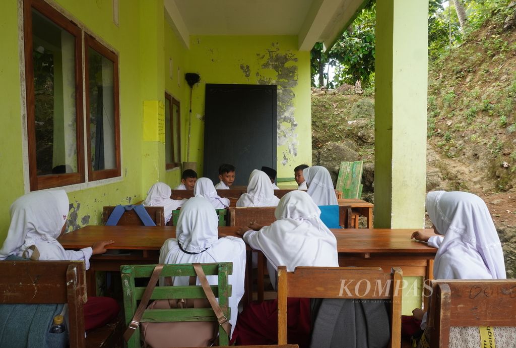 Siswa kelas III belajar di teras Madrasah Ibtidaiyah Pasawahan, Kecamatan Banjaranyar, Kabupaten Ciamis, Jawa Barat, Selasa (19/7/2022).  Sekolah itu ambruk saat bencana gempa bumi dan tanah bergerak pada tahun 2016. Lantaran keterbatasan biaya, pembangunan kembali sekolah itu belum juga selesai. 
