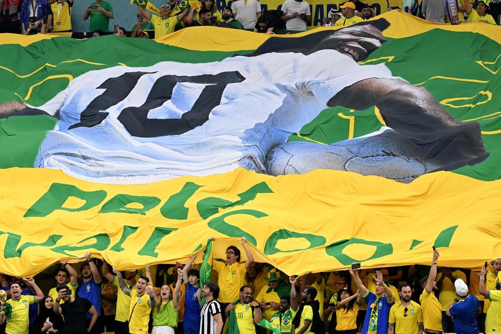 Bendera besar bergambar Pele dibentangkan pendukung Brasil saat melawan Kamerun di Stadion Stadium pada 2 Desember 2022. 