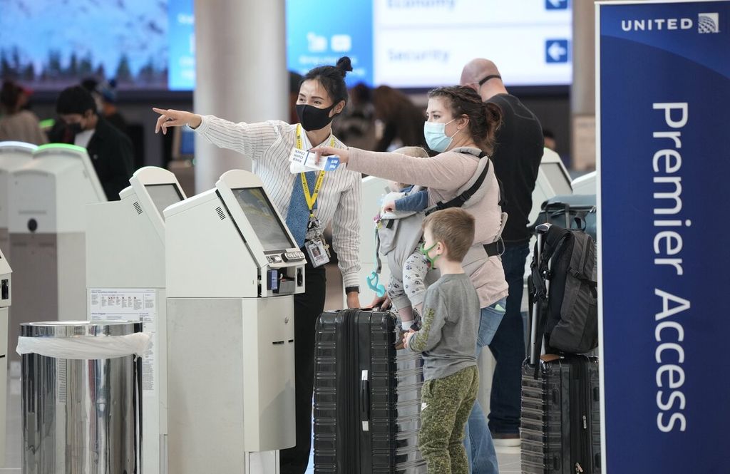 Anggota staf maskapai United Airlines mengarahkan penumpang pesawat terbang setelah daftar diri di konter pelaporan di terminal keberangkatan Bandara Internasional Denver, Colorado, Amerika Serikat, Minggu (26/12/2021). 