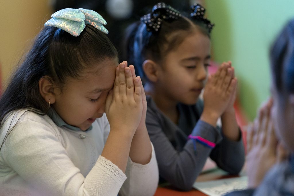 Gaby Meza Rodriguez (kiri) berdoa bersama anak-anak lain saat sesi Sekolah Minggu sementara orangtuanya menghadiri kebaktian gereja, 17 Desember 2023, di Fort Morgan, Colorado, AS.