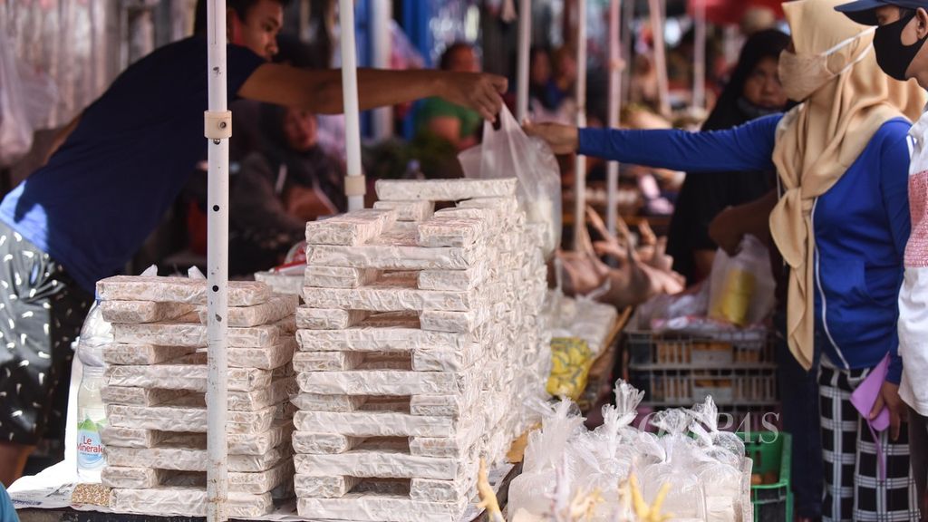 Pedagang tempe-tahu melayani pelanggan di Pasar Kebayoran Lama, Jakarta Selatan, Sabtiu (8/1/2021). Untuk menyiasati tingginya harga kedelai, pedagang tempe-tahu di kawasan tersebut tidak menaikkan harga jual, tetapi memperkecil ukuran tempe-tahu yang dijual.