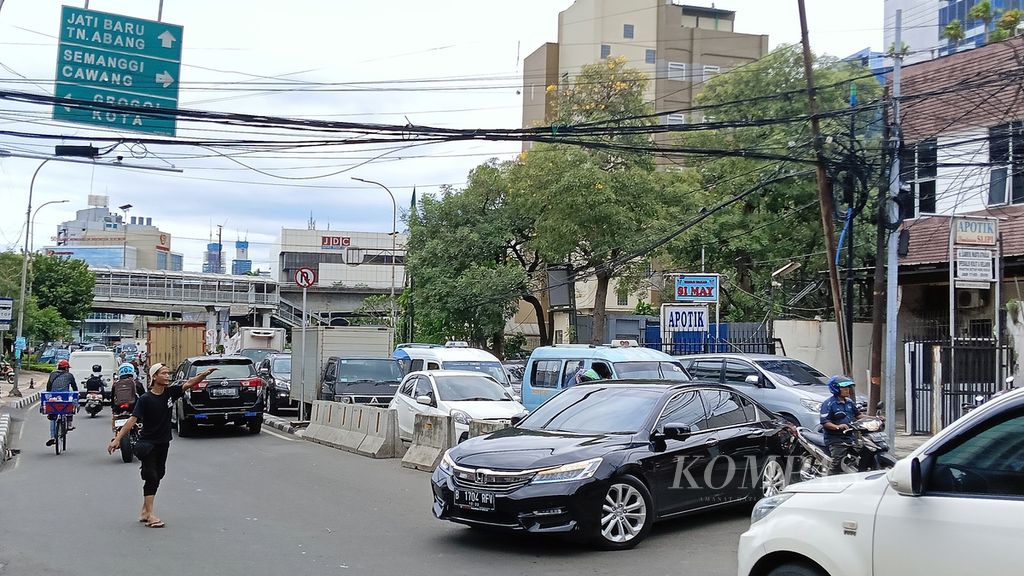 Seorang ”pak ogah” di Jalan Palmerah Utara, Jakarta Barat, saat mengarahkan kendaraan yang putar balik, Jumat (10/2/2023). Plang rambu dilarang belok dan putar balik tak diindahkan sehingga kerap menimbulkan kemacetan.