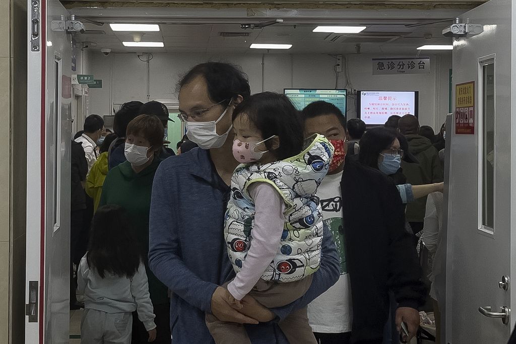 Seorang pria menggendong anak perempuan keluar dari ruang perawatan sebuah rumah sakit di Beijing, Senin (30/10/2023),
