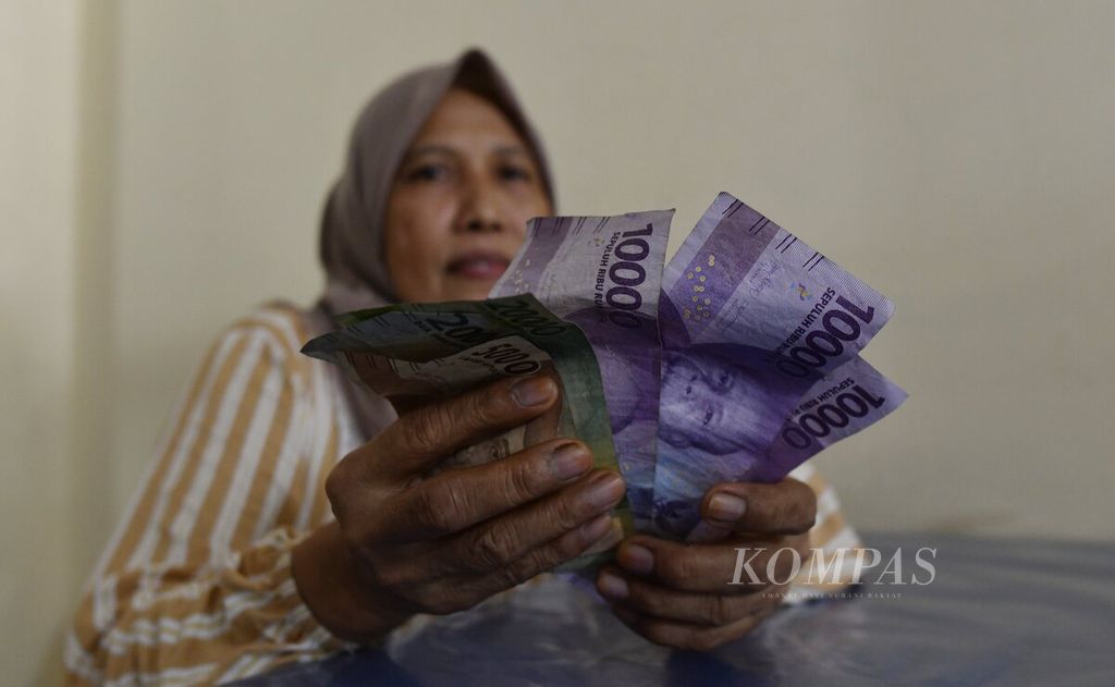Ibu Nur (55), yang membuka usaha warung makan di Sebatik, Kabupaten Nunukan, Kalimantan Utara, menunjukkan sejumlah uang rupiah, Sabtu (16/7/2022). Meski tinggal di perbatasan Indonesia-Malaysia, kesadaran dan kecintaan warga untuk menggunakan rupiah terus meningkat. 