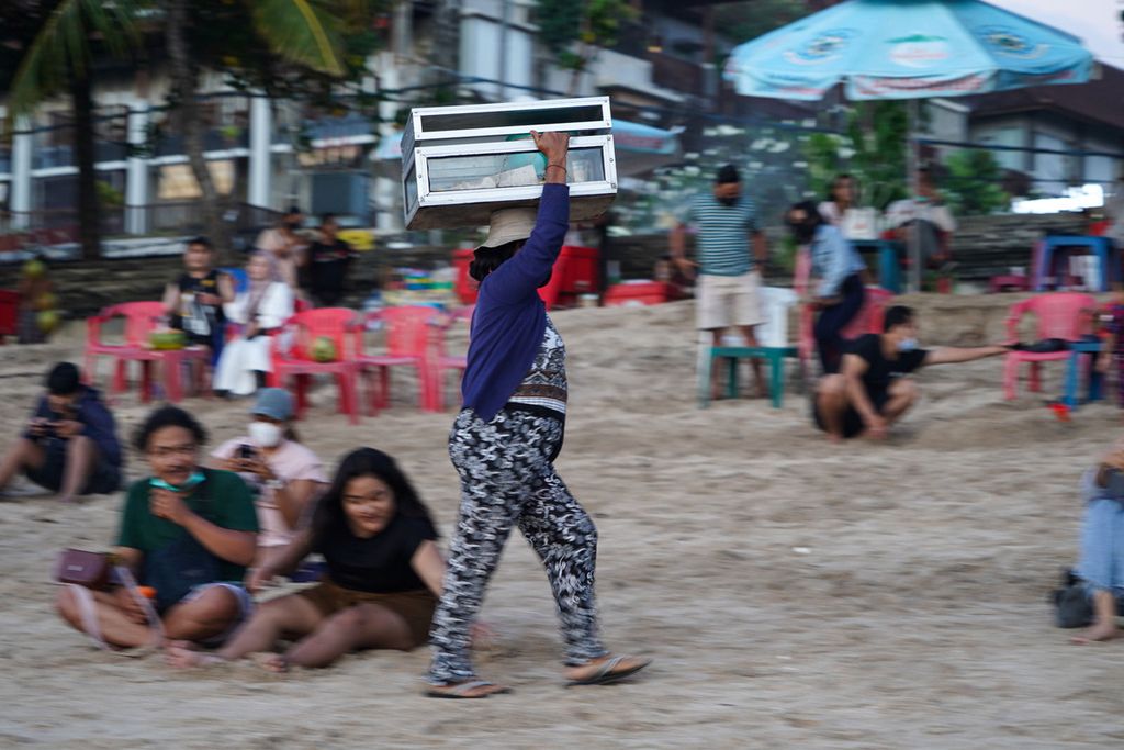 Traders peddle their wares at Kuta Beach, Bali, Monday (11/10/2021).