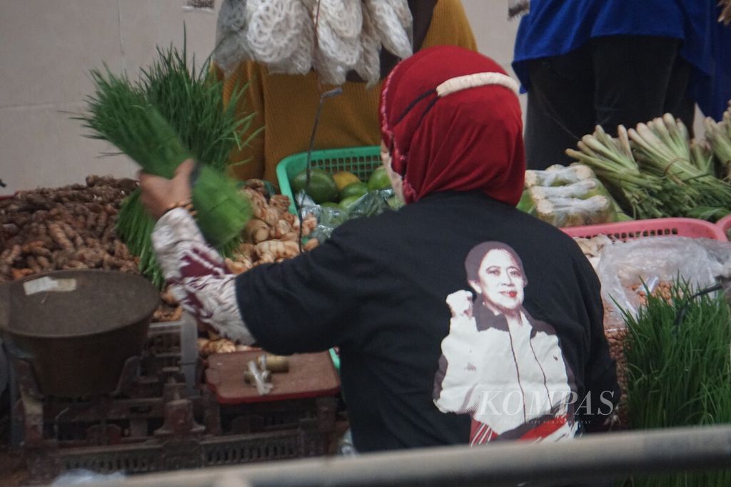 Seorang pedagang mengenakan kaus dari Ketua DPR Puan Maharani yang mengunjungi dan meresmikan Pasar Banjoemas di Kabupaten Banyumas, Jawa Tengah, Rabu (6/7/2022). Setelah peresmian itu, Puan berkeliling pasar sambil membagikan kaus bergambar dirinya.