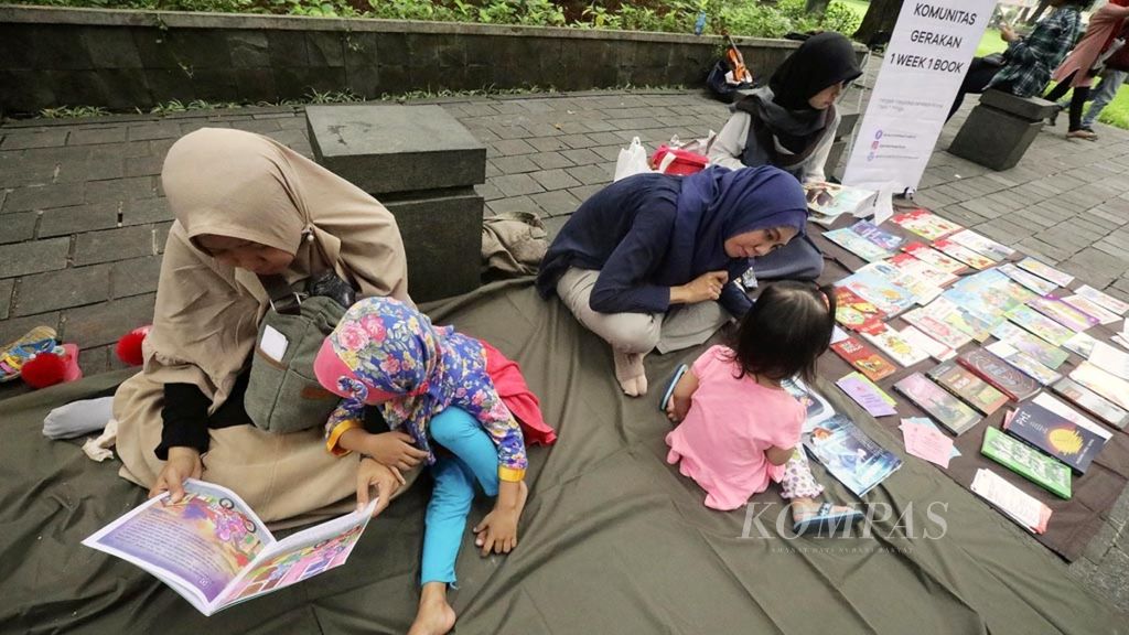 Pengunjung Taman Suropati, Menteng, Jakarta Pusat, membaca buku yang disediakan komunitas perpustakaan jalanan Komunitas One Week One Book, Minggu (20/1/2019). 