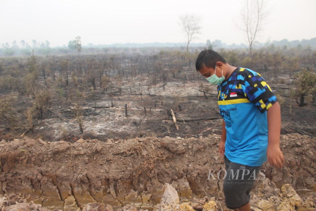Seorang anak melewati lahan bekas kebakaran di Desa Sungai Rambutan, Kecamatan Indralaya Utara, Kabupaten Ogan Ilir, Sumsel, Kamis (18/9/2019).