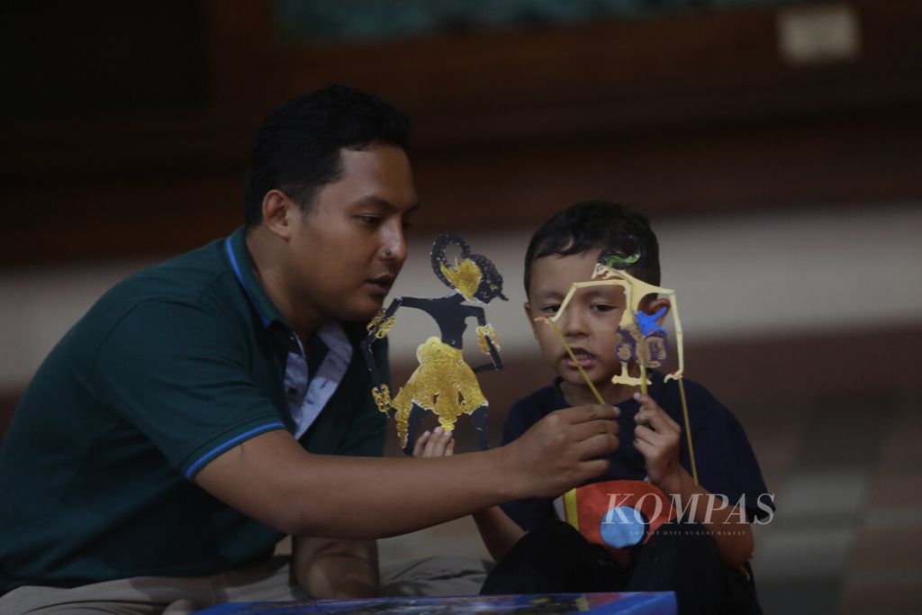 Pengunjung bermain wayang bersama anaknya dalam Pekan Wayang 2022 yang diselenggarakan di ruang Serbaguna Gedung Pewayangan Kautaman TMII, Jakarta, Selasa (8/11/2022). 