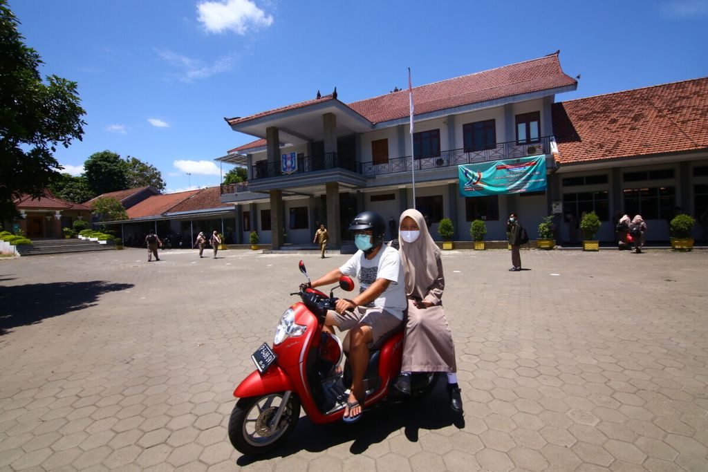 Seorang siswa tetap mengenakan masker ketika dijemput orangtunya pulang meninggalkan lingkungan sekolah di SMA Negeri 1 Giri Banyuwangi, Senin (16/11/2020). Sebanyak 7.861 siswa dari 57 SMA/SMK di Banyuwangi mengikuti uji coba sekolah tatap muka minggu ini.