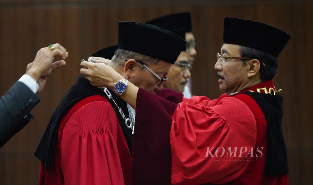 Ketua Mahkamah Konstitusi Suhartoyo memasangkan kalung hakim konstitusi kepada hakim konstitusi baru Arsul Sani yang menggantikan Wahiduddin Adams saat wisuda purnabhakti hakim konstitusi Wahiduddin Adams dan Manahan MP Sitompul di Gedung Mahkamah Konstitusi, Jakarta, Kamis (18/1/2024).