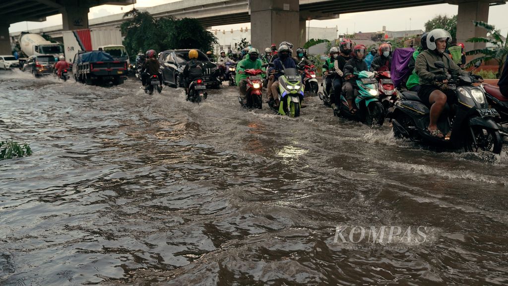 Pengguna jalan berhati-hati melintasi genangan di Jalan Raya Kalimalang, Duren Sawit, Jakarta Timur, Jumat (20/5/2022). Hujan dengan intensitas lebat dan drainase yang buruk mengakibatkan sejumlah genangan di jalan raya. 