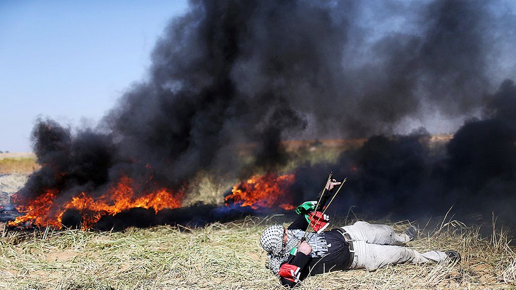 Seorang pejuang Palestina  melontarkan batu-batu dengan katapel, Sabtu (31/3/2018), saat bentrok dengan tentara Israel di perbatasan Gaza-Israel, Jalur Gaza bagian selatan, dalam unjuk rasa menuntut hak warga Palestina kembali ke Tanah Air.  