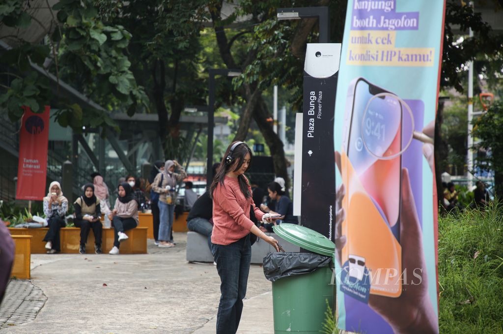 Seorang pengunjung membuang sampah pada tempat yang telah disediakan di taman literasi Martha Christina Tiahahu di kawasan Blok M, Jakarta Selatan, Jumat (30/6/2023). Kebersihan taman kota juga menjadi tanggung jawab bersama pengunjung. Edukasi untuk membuang sampah pada tempatnya terus digalakkan.