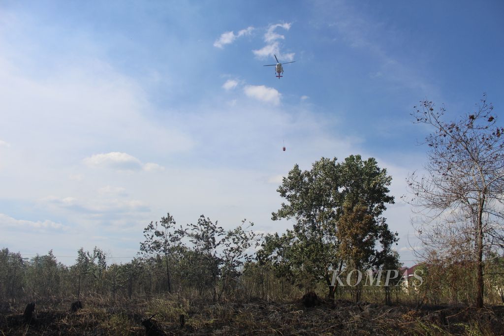 Helikopter <i>water bombing</i> membantu pemadaman api di lahan kosong dekat kompleks permukiman warga Jalan Matal. Kota Palangkaraya, Kalimantan Tengah, Minggu (13/8/2023). 