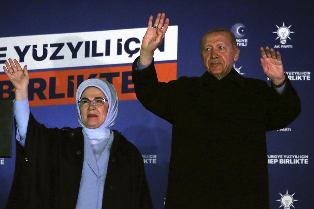 Calon presiden petahana Recep Tayyip Erdogan dan istrinya, Emine, melambaikan tangan kepada para pendukungnya yang berkumpul di markas Partai AKP di Ankara, Senin (15/5/2023), seusai unggul pada putaran pertama pemungutan suara. Erdogan memenangi putaran kedua dan membuatnya menjadi Presiden Turki hingga 2028. 