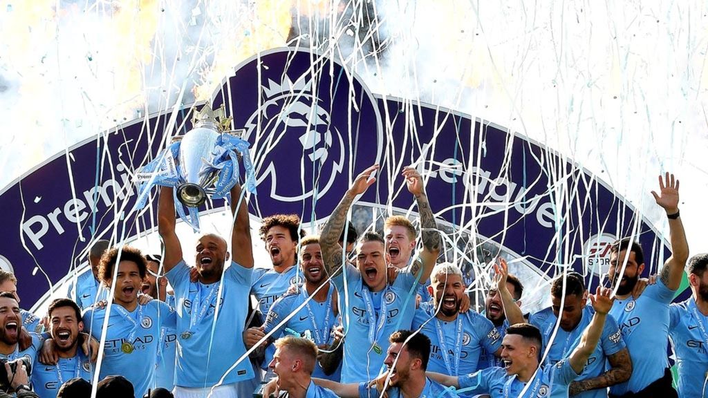 Kapten tim Manchester City, Vincent Kompany, mengangkat trofi Liga Inggris dalam perayaan gelar juara yang diraih setelah menang 4-1 di markas Brighton & Hove Albion, Minggu (12/5/2019).