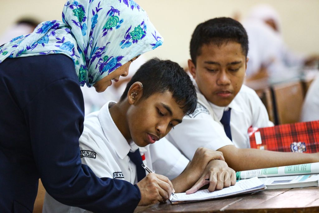 Guru membimbing siswa kelas IX yang mengalami hambatan pendengaran di SMP Negeri 226, Pondok Labu, Cilandak, Jakarta Selatan, Selasa (21/1/2020). SMP Negeri 226 merupakan sekolah yang ramah bagi disabilitas. 
