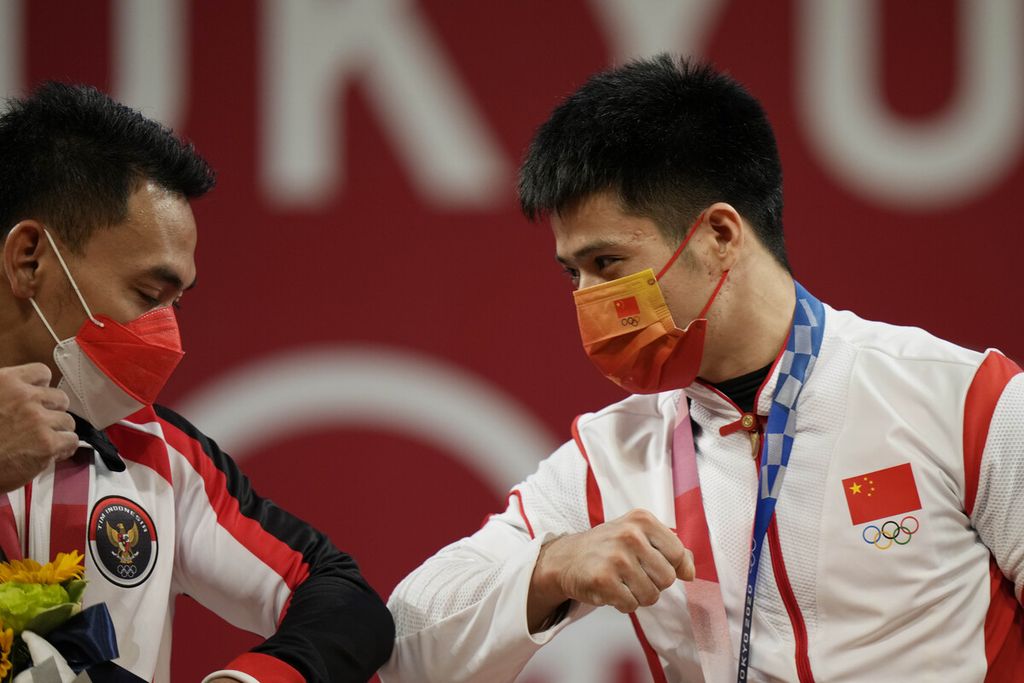 Lifter Indonesia, Eko Yuli Irawan (kiri), meraih medali perak dan Li Fabin (China) meraih emas dalam cabang angkat besi 61 kg putra Olimpiade Tokyo 2020 di Tokyo, Jepang, Minggu (25/7/2021).