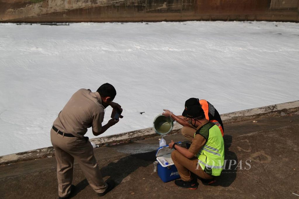 Petugas dari Suku Dinas Lingkungan Hidup mengambil sampel air Kanal Timur yang tercemar di pintu air Malaka Sari, Jakarta Timur, akhir Juni 2020.