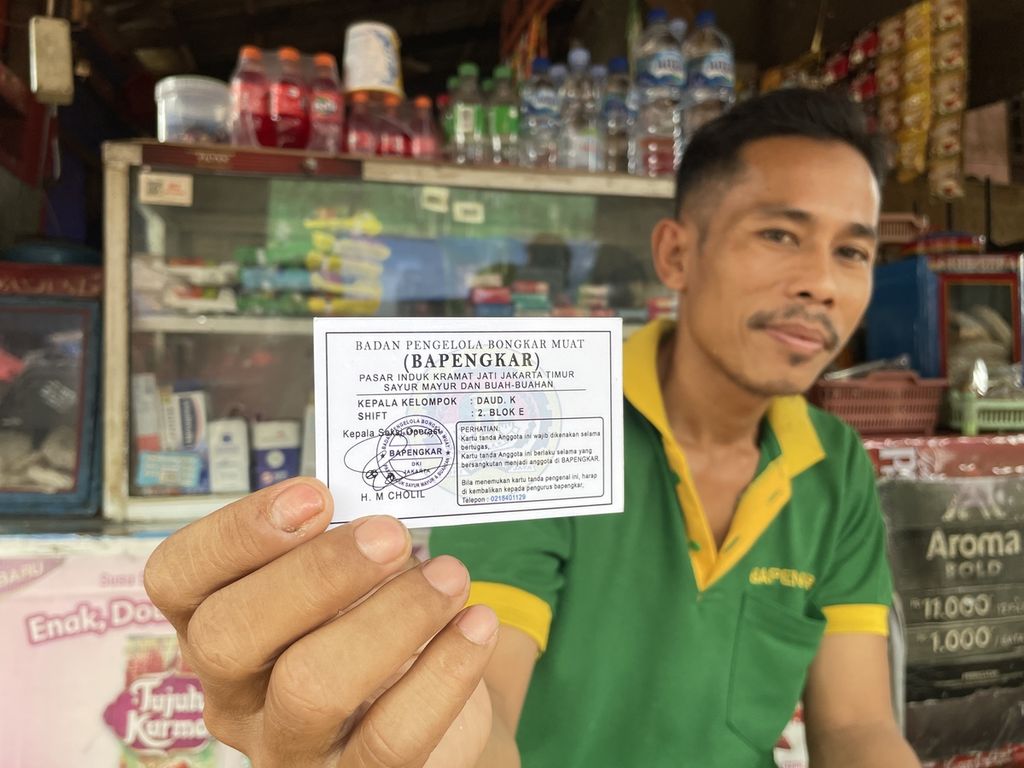 Santibi (43) menunjukkan kartu tanda keanggotaan Badan Pengelola Bongkar Muat (Bapengkar) di Pasar Induk Kramat Jati, Jakarta Timur, Rabu (8/3/2023). Selain kartu tanda keanggotaan, kuli yang bergabung dengan Bapengkar juga mendapatkan kaus untuk bekerja.