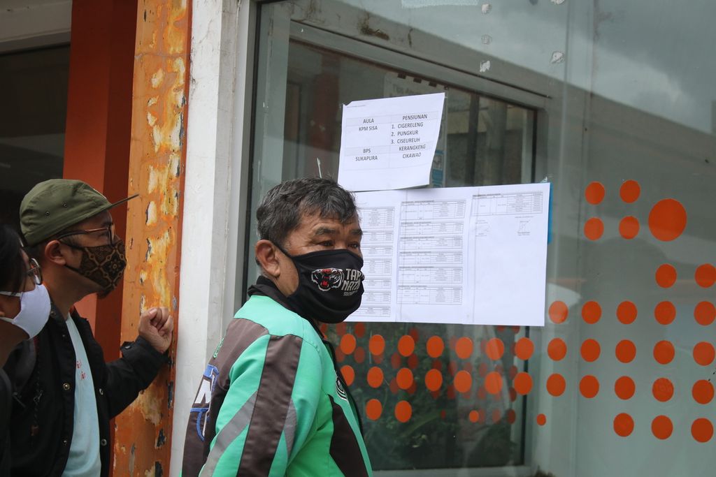 Salah seorang warga mengamati pengumuman dalam penyerahan bantuan sosial dari Pemerintah Provinsi Jawa Barat di Kantor Pos Jalan Asia Afrika, Kota Bandung, Selasa (29/12/2020). Sebagian warga tidak menerapkan protokol kesehatan seperti berkerumun dan tidak menggunakan masker dengan benar.