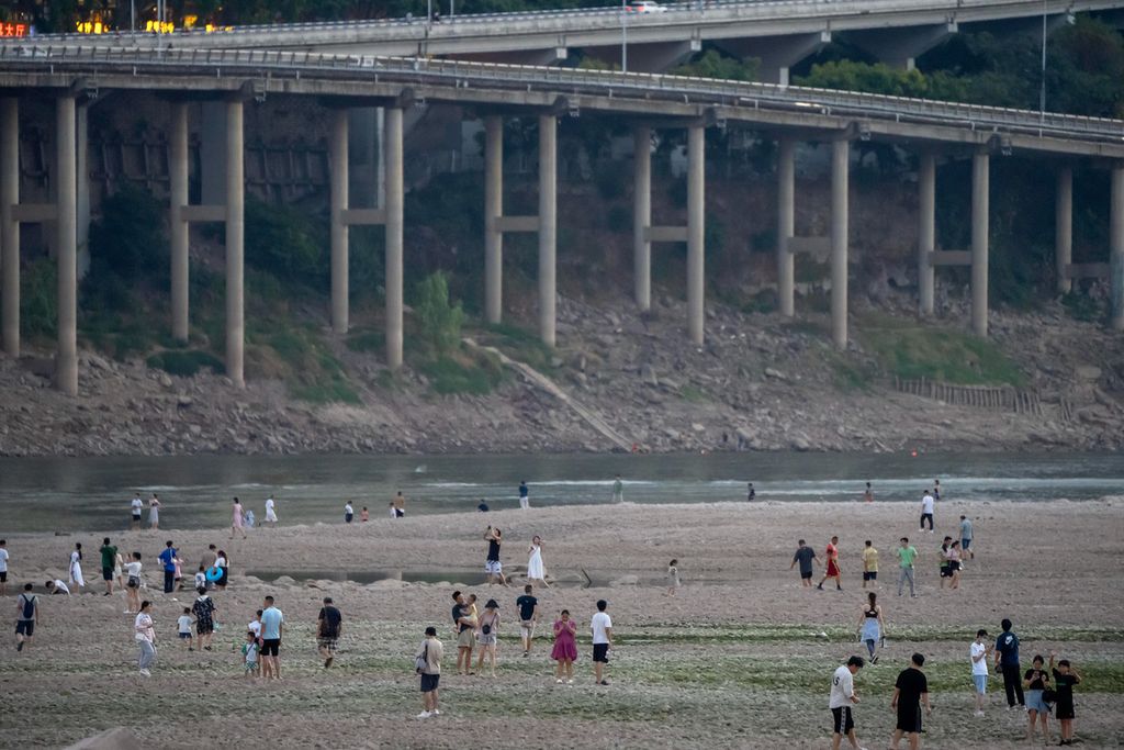Warga berjalan-jalan di dasar Sungai Jialing yang merupakan anak Sungai Yangtze di kota Chongqing, Provinsi Sichuan, China pada hari Sabtu (20/8/2022). Musim kemarau ekstrem membuat air sungai surut drastis.   