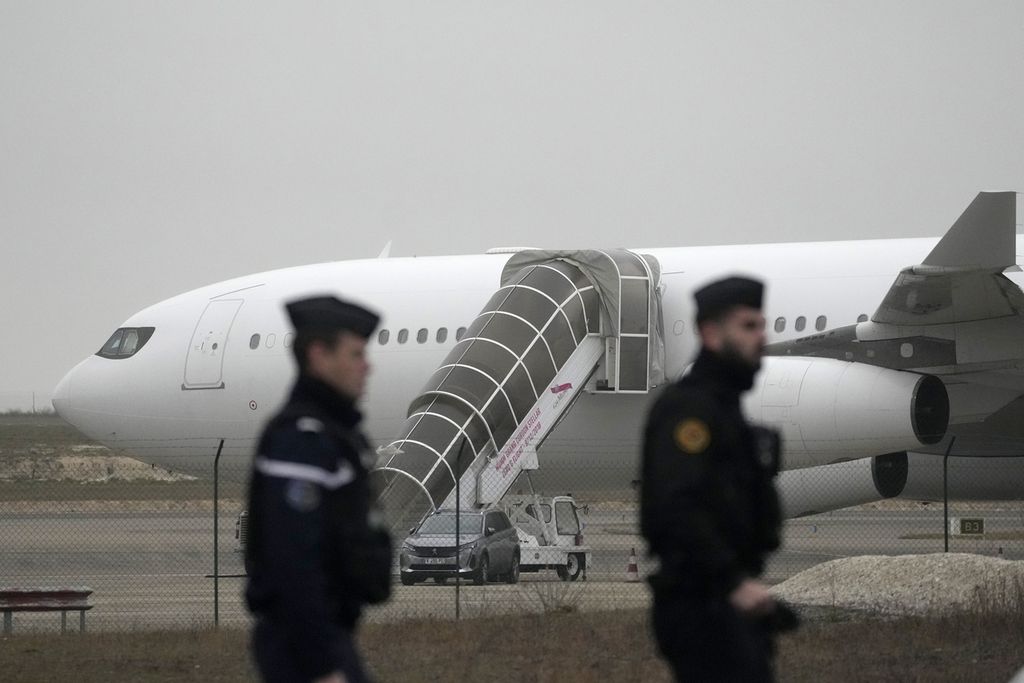 Aparat Perancis patroli dekat pesawat yang ditahan di Bandara Vatry, Champagne, pada Senin (25/12/2023). Pesawat itu diduga mengangkut korban perdagangan orang.