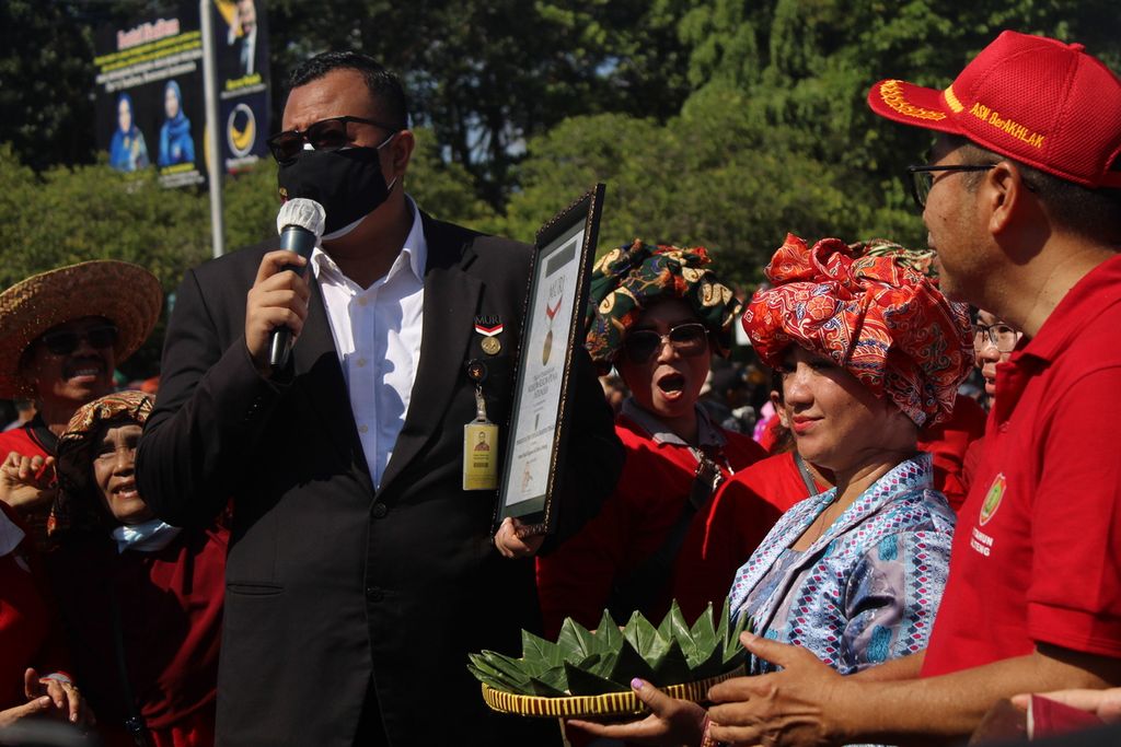 Senior Manager Museum Rekor Dunia Indonesia (MURI) Awan Rahargo memberikan penghargaan MURI kepada perwakilan peserta mangenta di Palangkaraya, Minggu (22/5/2022). Mangenta merupakan masakan khas Dayak yang terbuat dari ketan.