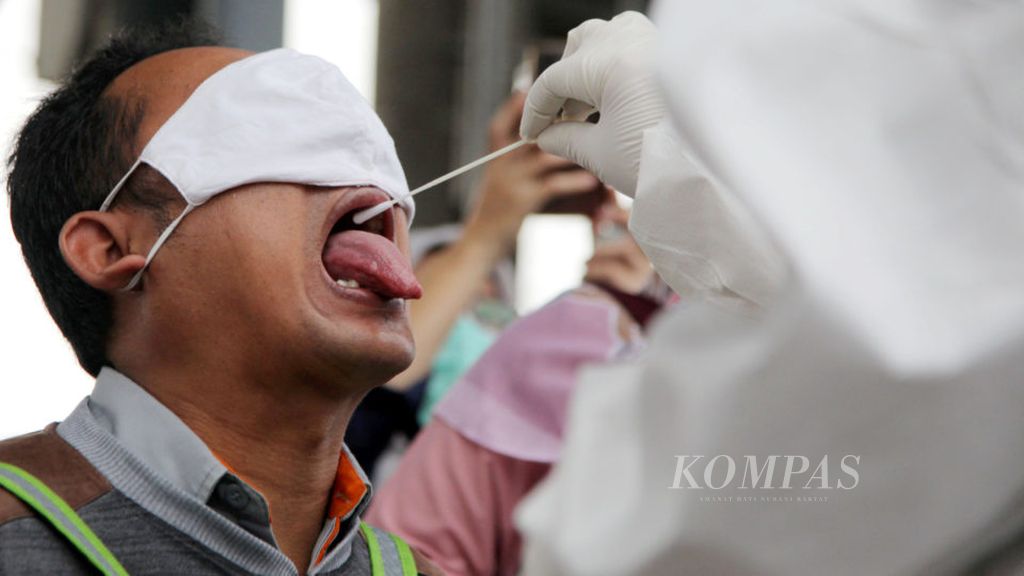 Salah satu calon penumpang KRL diambil sampel cairan dari rongga mulutnya saat pelaksanaan tes usap (swab) reaksi berantai polimerase (Polymerase Chain Reaction) Covid-19 di Stasiun Bojong Gede, Kabupaten Bogor, Senin (11/5/2020).