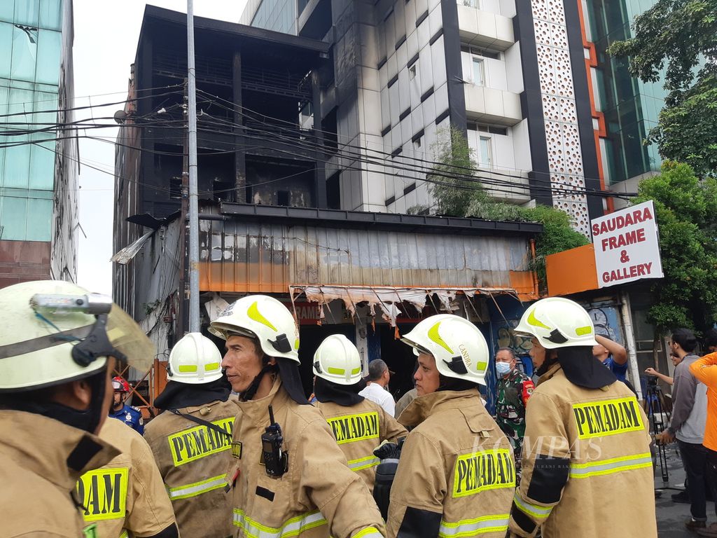 Petugas pemadam kebakaran terus berjibaku memastikan api padam di Toko Frame ”Saudara” di Mampang Prapatan, Jakarta Selatan, Jumat (19/4/2024). Tujuh orang tewas dalam peristiwa ini.