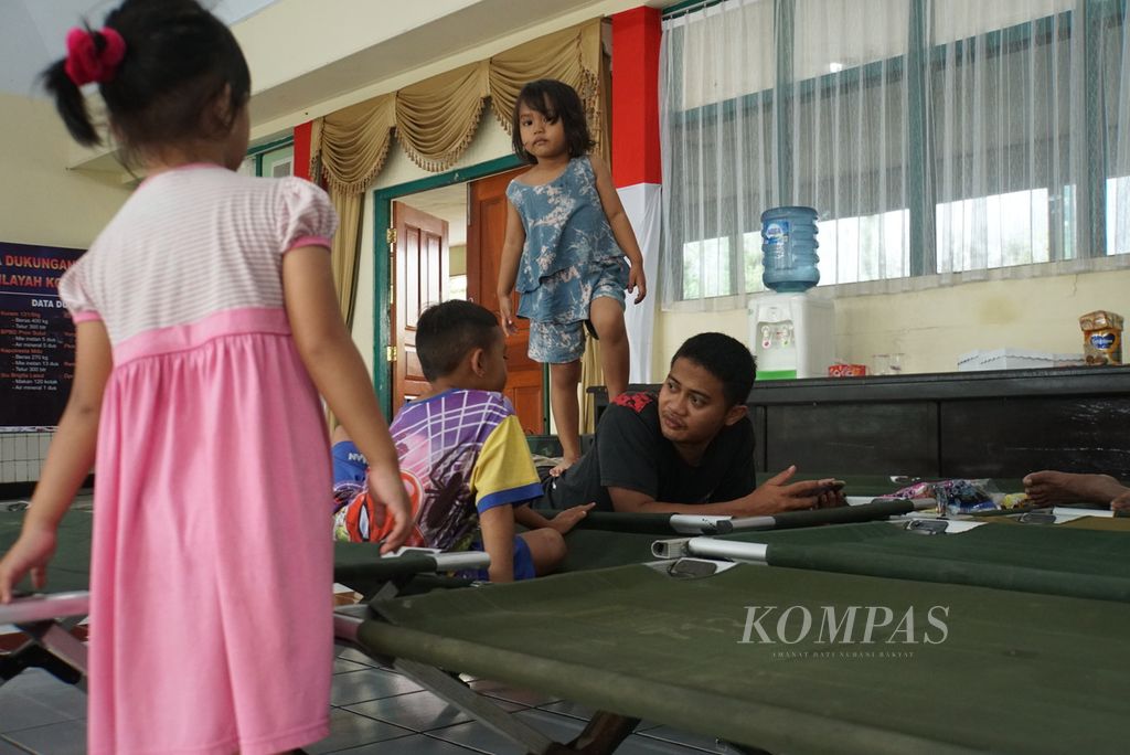 Pengungsi bersantai di aula markas Komando Resor Militer (Korem) 131/Santiago di Manado, Sulawesi Utara, Sabtu (28/1/2023). Sehari sebelumnya, Manado dilanda banjir dan tanah longsor yang menewaskan sedikitnya lima orang.
