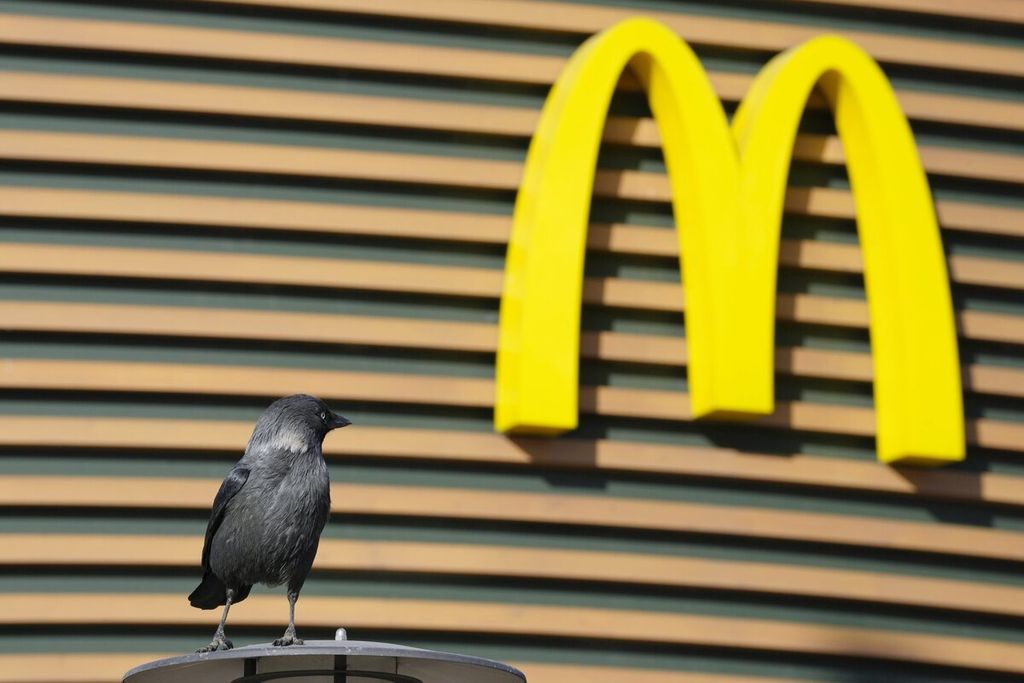 Seekor burung bertengger di atas lampu di depan restoran McDonald's yang tutup di St. Petersburg. 