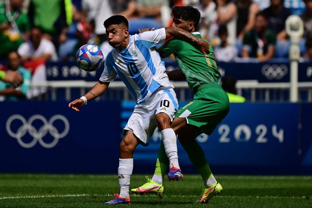 Gelandang Argentina, Thiago Almada (kiri), berebut bola dengan bek Irak, Mustafa Saadoon, pada laga Grup B cabang sepak bola Olimpiade Paris 2024 di Stadion Lyon, Perancis, Sabtu (27/7/2024). Argentina menang 3-1.