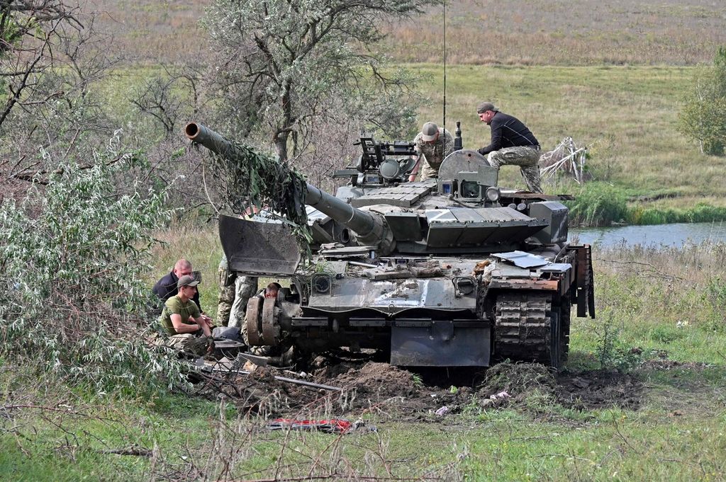 Prajurit Ukraina bekerja di sebuah tank yang ditinggalkan pasukan Rusia di wilayah utara Kharkiv, Ukraina, Selasa (20/9/2022). 