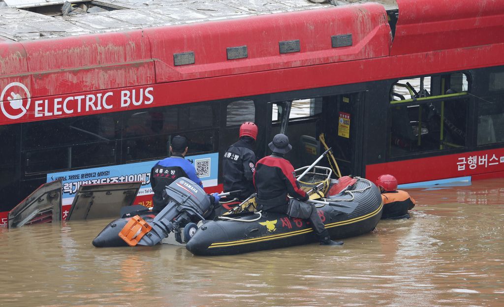 Tim penyelamat menggunakan perahu karet untuk melihat sisi dalam sebuah bus yang terjebak banjir bandang di terowongan di kota Cheongju, Korea Selatan, Minggu (16/7/2023). Hujan yang terus turun sejak 9 Juli telah mengakibakan kota ini dilanda banjir.   