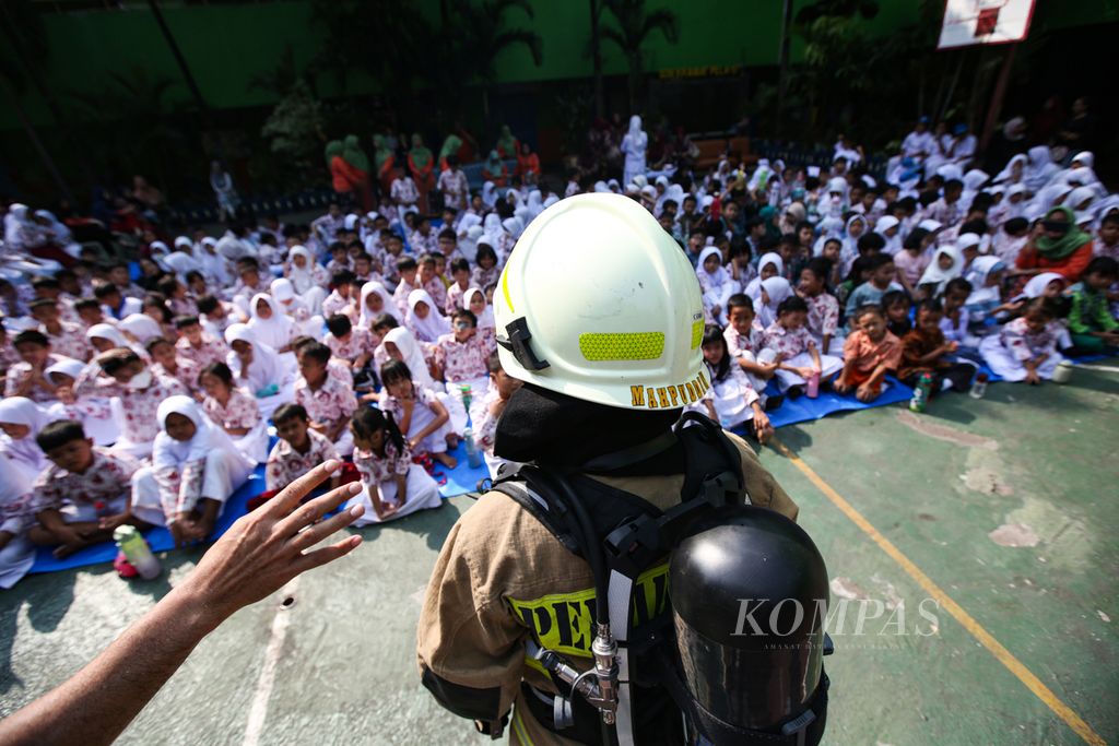 Petugas pemadam kebakaran sektor Kebayoran Baru menjelaskan berbagai alat yang digunakan untuk pemadaman kebakaran kepada para siswa, guru, dan orangtua siswa dalam kegiatan masa pengenalan lingkungan sekolah di SD Negeri Kramat Pela 07, Jakarta Selatan, Jumat (19/7/2024).