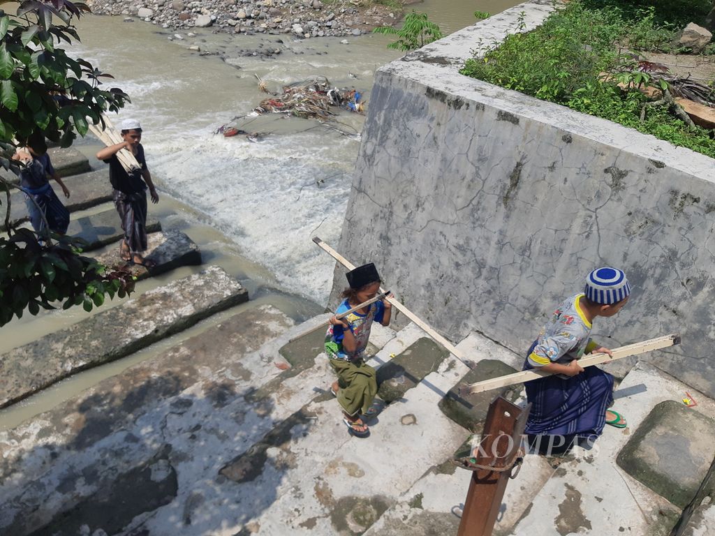 Warga melintasi sungai di Benda Kerep, Kelurahan Argasunya, Kecamatan Harjamukti, Kota Cirebon, Jawa Barat, Senin (12/2/2024). Sepeda motor dan mobil tidak bisa masuk ke kawasan itu karena tidak ada jembatan.