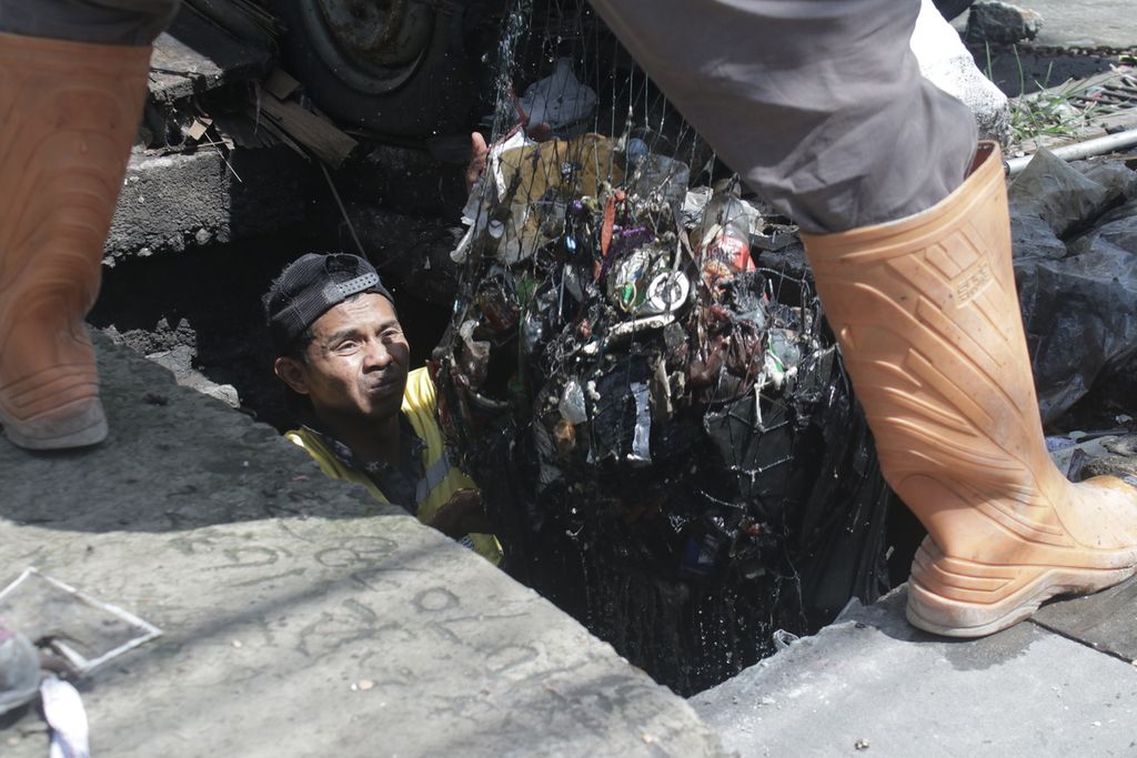 Petugas Dinas Pekerjaan Umum Kota Bandung mengernyitkan dahi untuk menahan aroma busuk dari sampah yang diangkut dari saluran air di Jalan Raya Kopo, Kota Bandung, Jawa Barat, Rabu (3/11/2021).
