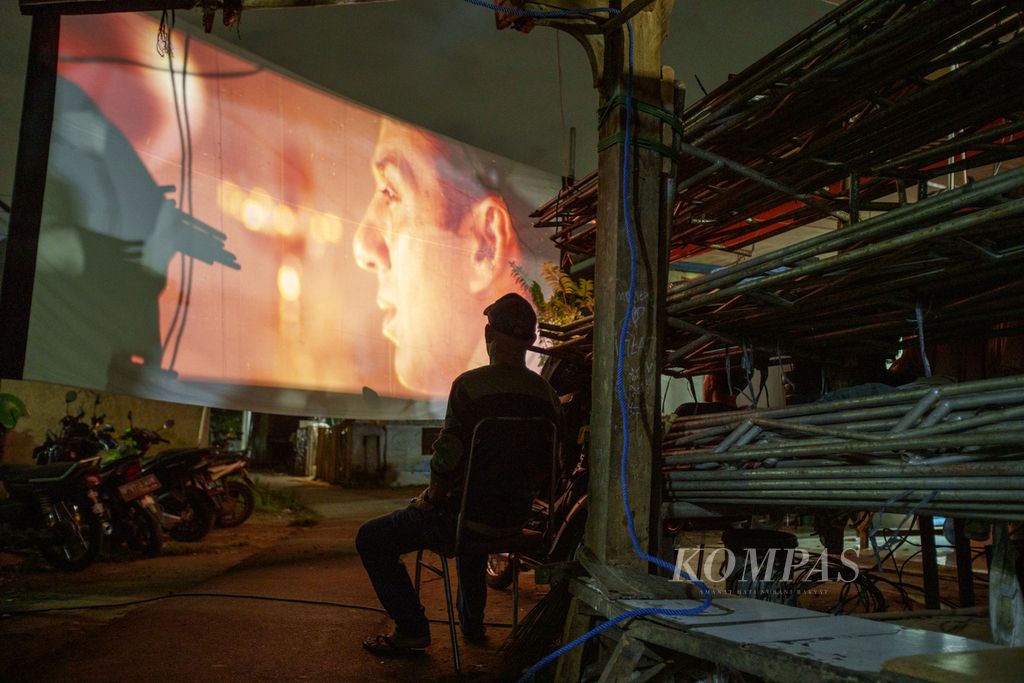 Warga menonton layar tancap di kawasan Ciputat, Tangerang Selatan, Banten. 