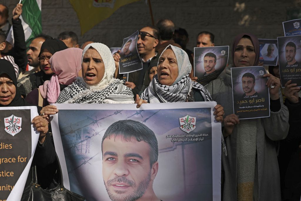 Pengunjuk rasa berkumpul di luar kantor Palang Merah Internasional di Gaza City, Selasa (27/12/2022), untuk menuntut jenazah tahanan Palestina, Nasser Abu Hamid, dikembalikan. Abu Hamid, tokoh senior Fatah, meninggal akibat kanker dalam penjara Israel.  