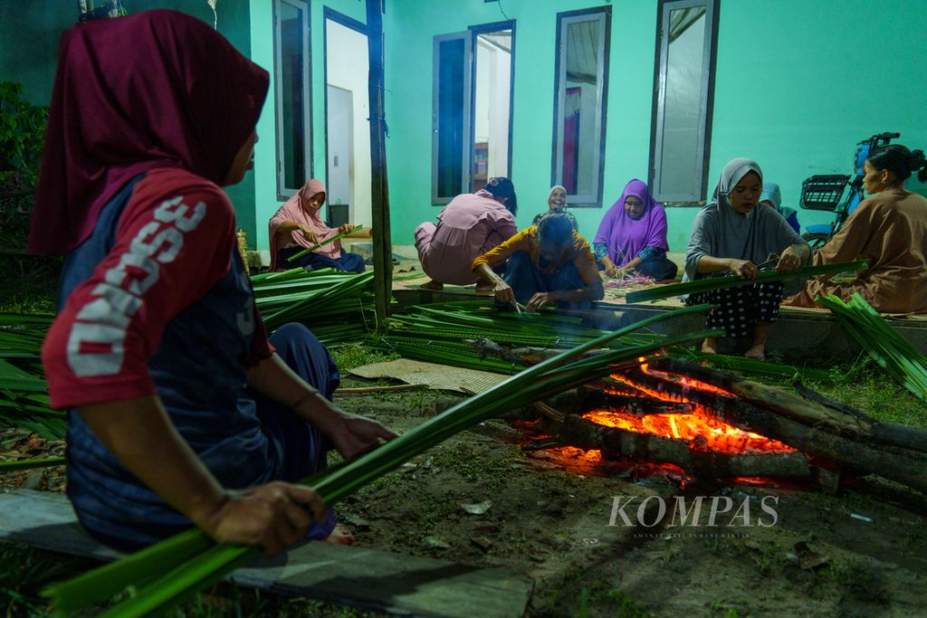 Kaum perempuan di desa Danau Lamo, Kecamatan Maro Sebo, Muaro Jambi, sedang melayukan daun pandan dengan membakarnya di atas api, Selasa (7/5/2024). Daun pandan ini menjadi bahan utama untuk menganyam aneka macam kerajinan. 