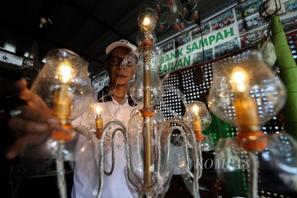 Rahamatullah (44) menyelesaikan pembuatan lampu hias dari bahan botol plastik di Bank Sampah Persatuan, Kelurahan Pondok Kelapa, Kecamatan Duren Sawit, Jakarta Timur.