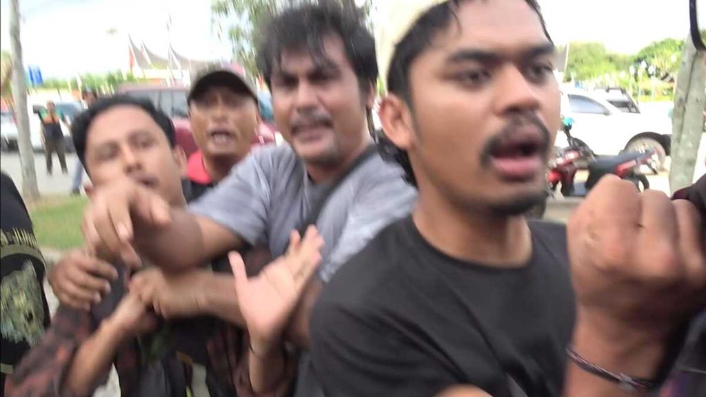 Anggota polisi (kanan) memegang kerah dan mengancam jurnalis saat liputan pemulangan paksa massa aksi dari Pasaman Barat di halaman Masjid Raya Sumatera Barat, Kota Padang, Sumbar, Sabtu (5/8/2023).
