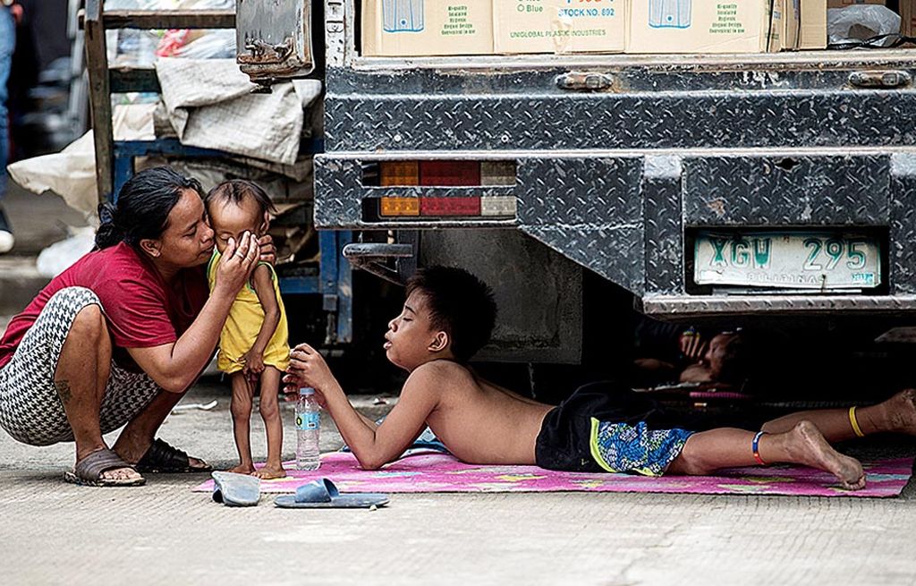 Seorang ibu mencium anaknya yang tengah berada di dekat truk di Manila, Filipina, Kamis (3/8). Presiden Filipina Rodrigo Duterte  menghadapi tantangan besar dalam isu keamanan dan  peredaran narkoba. Jika gagal mengatasi kedua isu itu, ia dinilai  akan kesulitan  mengatasi problem kemiskinan di negara itu secara optimal.  
