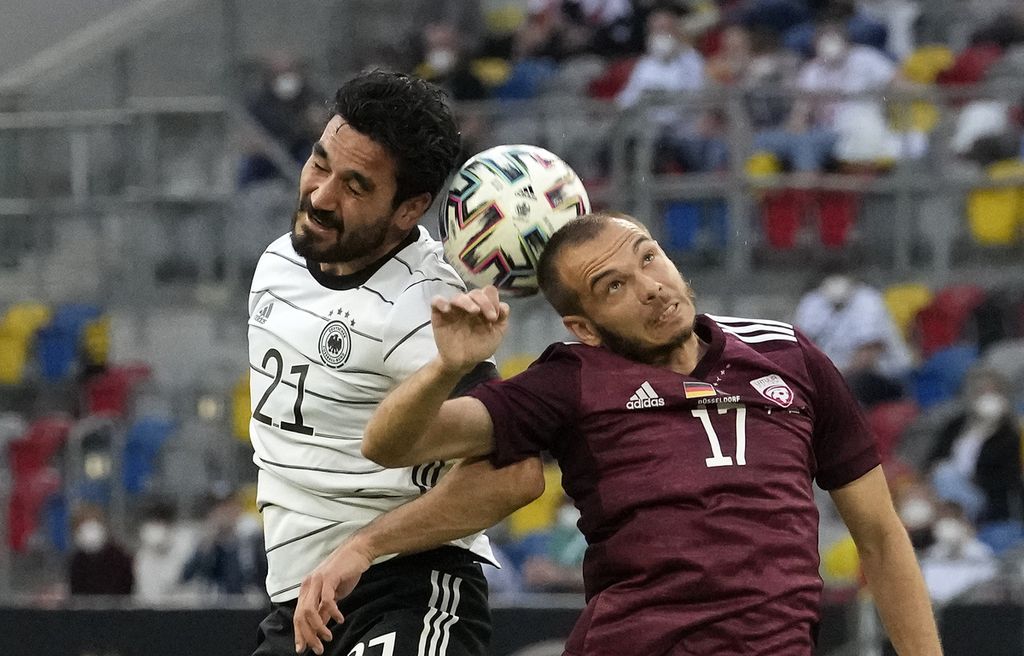 Pemain Jerman, Ilkay Gundogan (kiri) terlibat duel udara dengan pemain Latvia, Arturs Zjuzins saat kedua tim bertanding pada laga persahabatan jelang Piala Eropa 2020 di Merkur Spiel Arena, Jerman, Selasa (8/6/2021) dini hari WIB. Jerman menang 7-1. 
