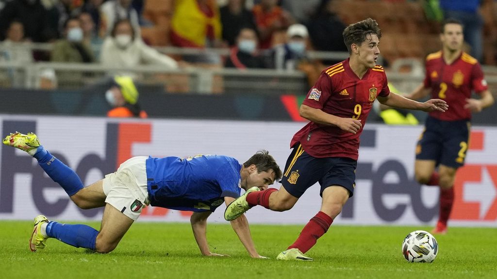 Penyerang Italia, Federico Chiesa (kiri) terjatuh saat berebut bola dengan pemain depan Spanyol, Gavi. Gol kemenangan La Furia Roja diboyong oleh Ferran Torres di menit ke-17 dan 45+2. Italia memperkecil kekalahan melalui Lorenzo Pellegrini (83'). 