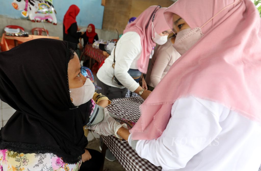 Petugas mengukur tekanan darah warga saat menerima pelayanan Pos Binaan Terpadu (Posbindu) RW 007 Pondok Kelapa, Jakarta Timur, Senin (16/1/2023).